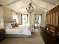 Stylish bedroom interior featuring a rustic chandelier, cozy bedding, and elegant wooden furniture.
