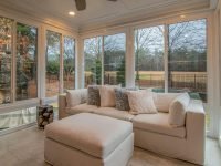 Spacious sunroom with contemporary sofa and large windows offering a serene outdoor view.